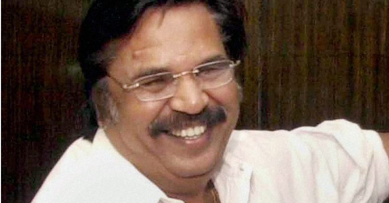 Smiling man with glasses and a mustache wearing a white shirt, looking slightly to the left.