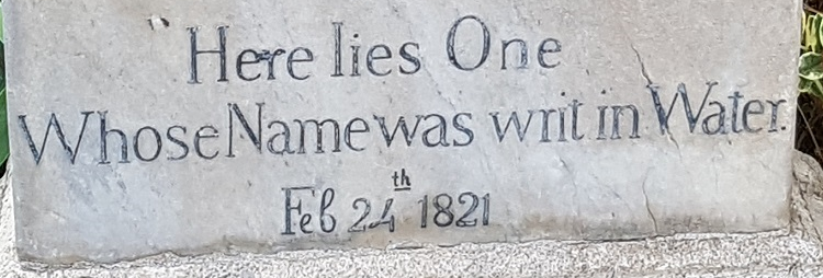Stone gravestone with the epitaph 'Here lies One Whose Name was writ in Water.' and the date 'Feb 24 1821' carved into it.
