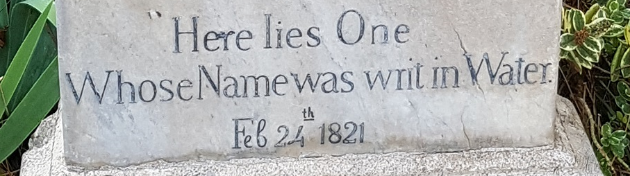 Stone gravestone with the epitaph 'Here lies One Whose Name was writ in Water.' and the date 'Feb 24 1821' carved into it.