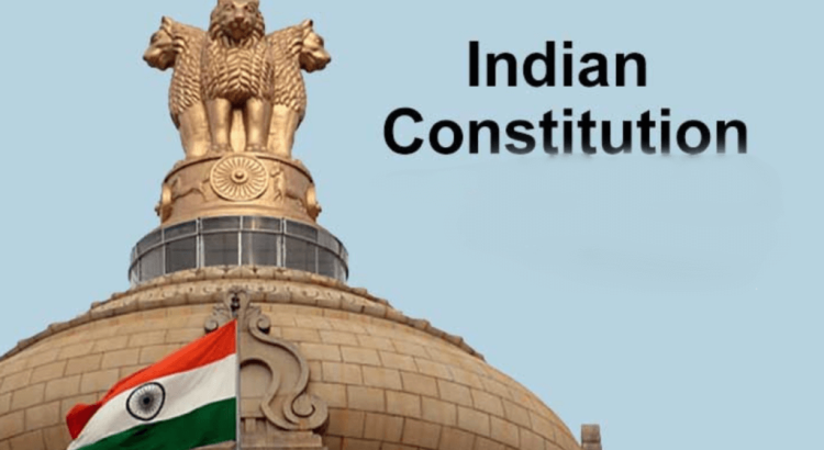 Indian flag raised beside a domed statue with the Ashoka emblem, over a pale blue sky, captioned 'Indian Constitution'